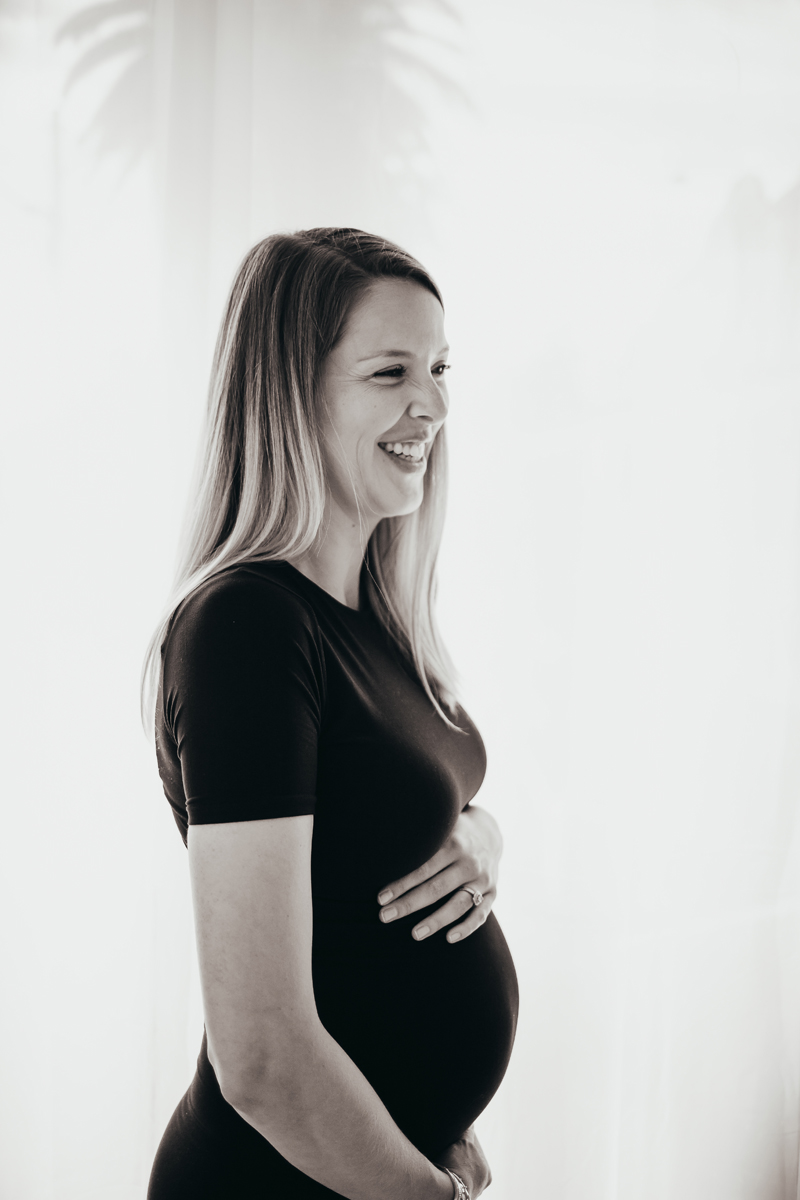 Temecula Maternity Photographer, woman smiling while holding her belly