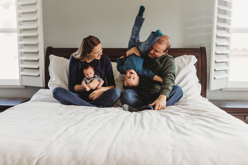 Temecula Newborn Photographer, mother and father sitting in bed with toddler and newborn baby